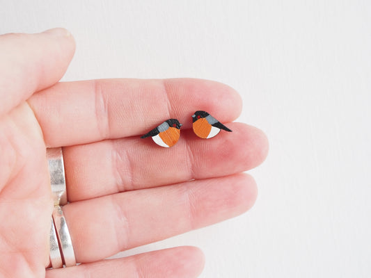 Bullfinch earrings held in hand, hand painted bird studs inspired by garden birds in the UK.