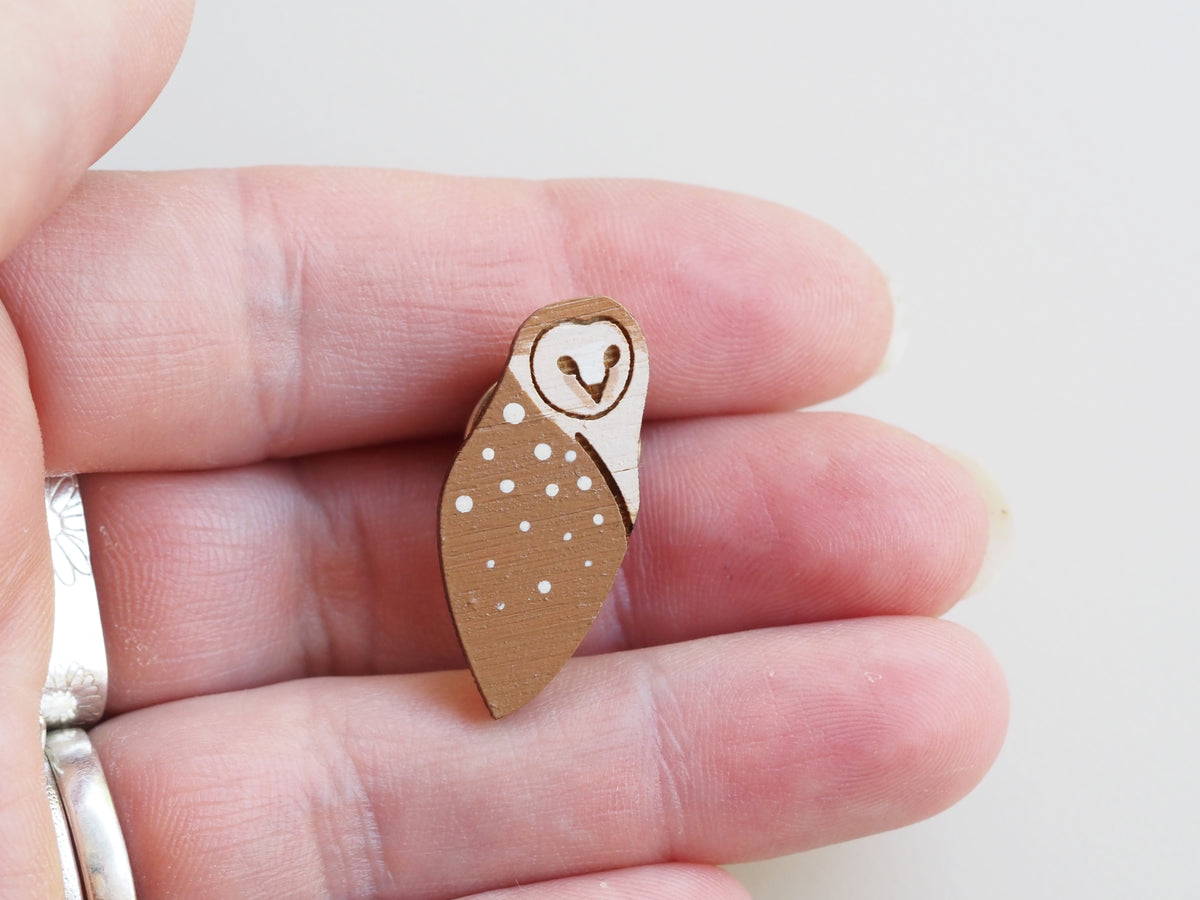 Hand-painted Mini Barn Owl Pin Badge held in hand, showcasing detailed design and cute features.