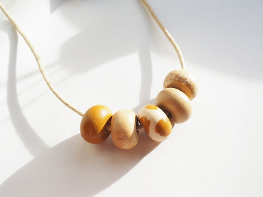 Ochre Wooden Bead Necklace featuring hand-painted wooden beads in mustard and cream shades.