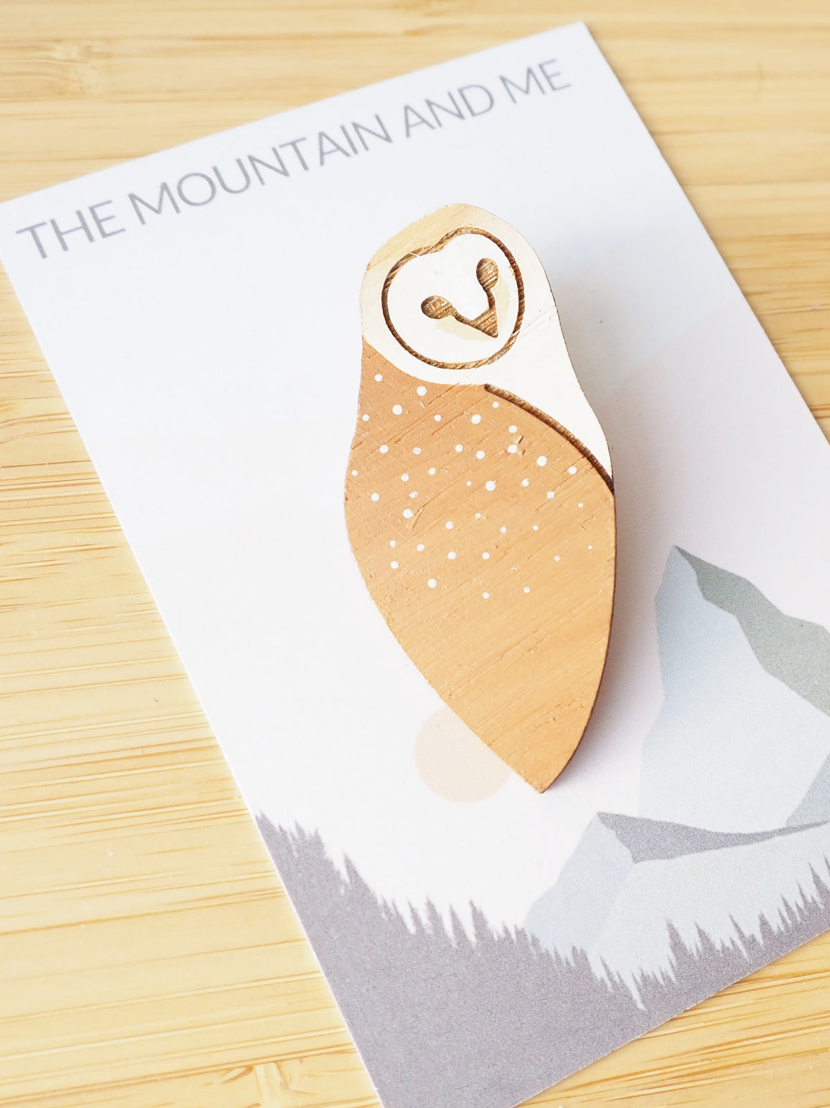 Barn owl brooch hand painted on bamboo with detailed illustration and earthy colors, displayed on branded card.