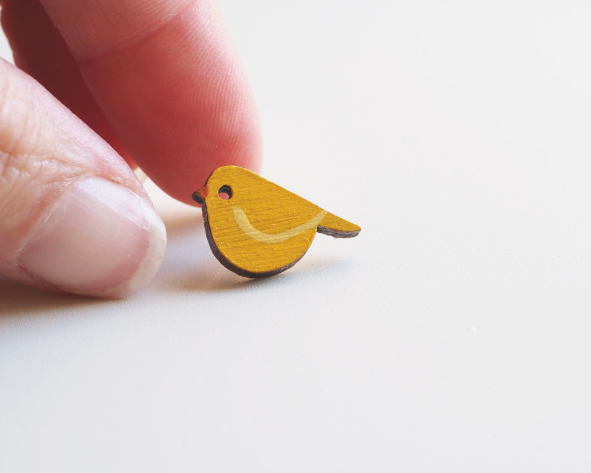 Mini Yellow Canary pin badge held between fingers, showcasing hand-painted bamboo bird design.