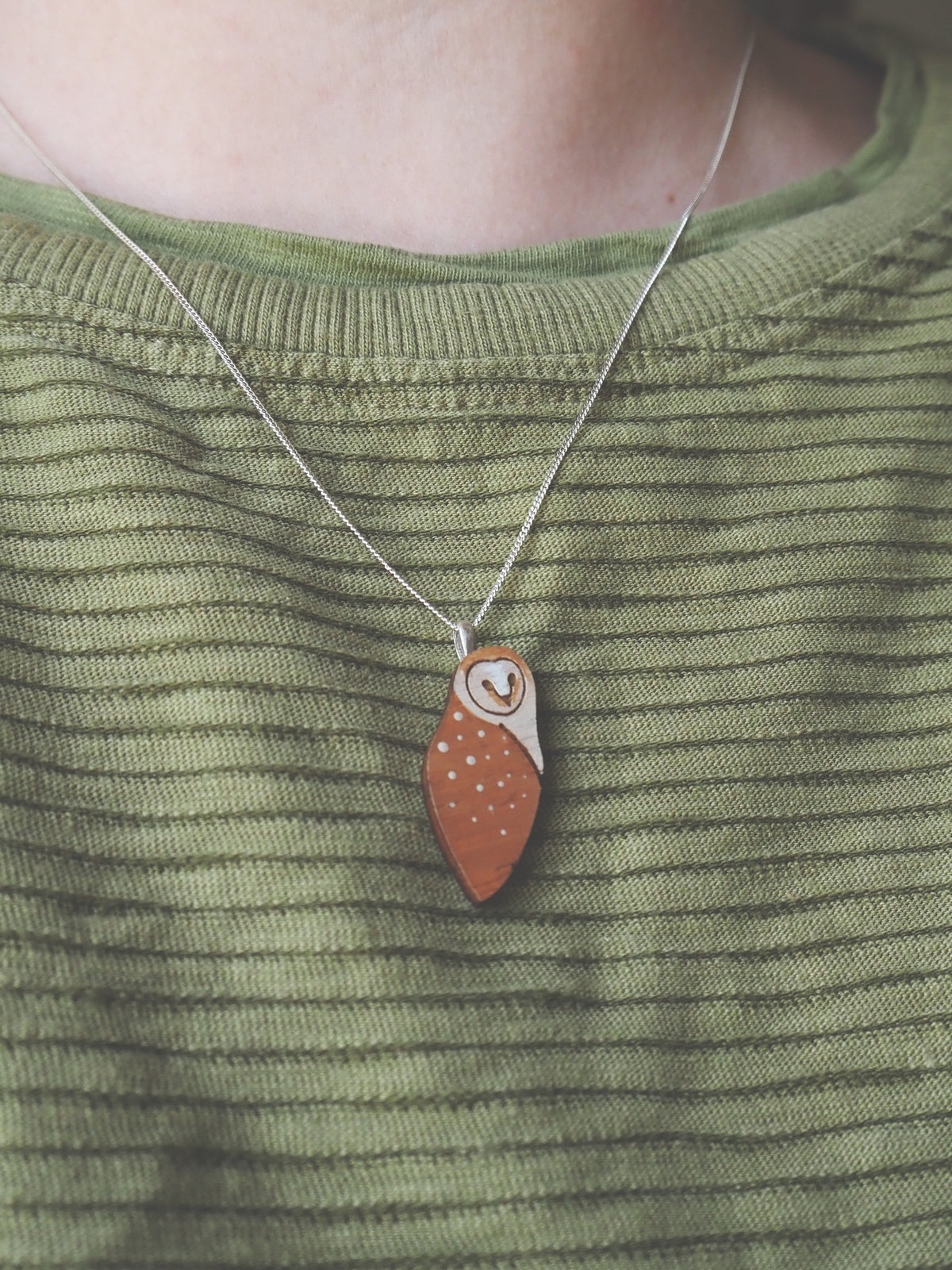 Barn Owl Necklace - Sterling Silver pendant worn on a person with a green striped shirt.