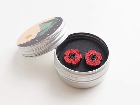 Poppy earrings in a tin box with a scenic lid, featuring hand-painted red wooden flower studs.